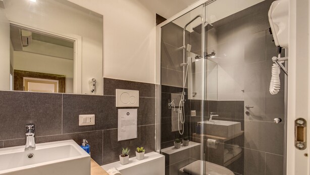 A modern bathroom with a glass-enclosed shower, a standalone sink, and a toilet. - Tritone Top House (Rome)