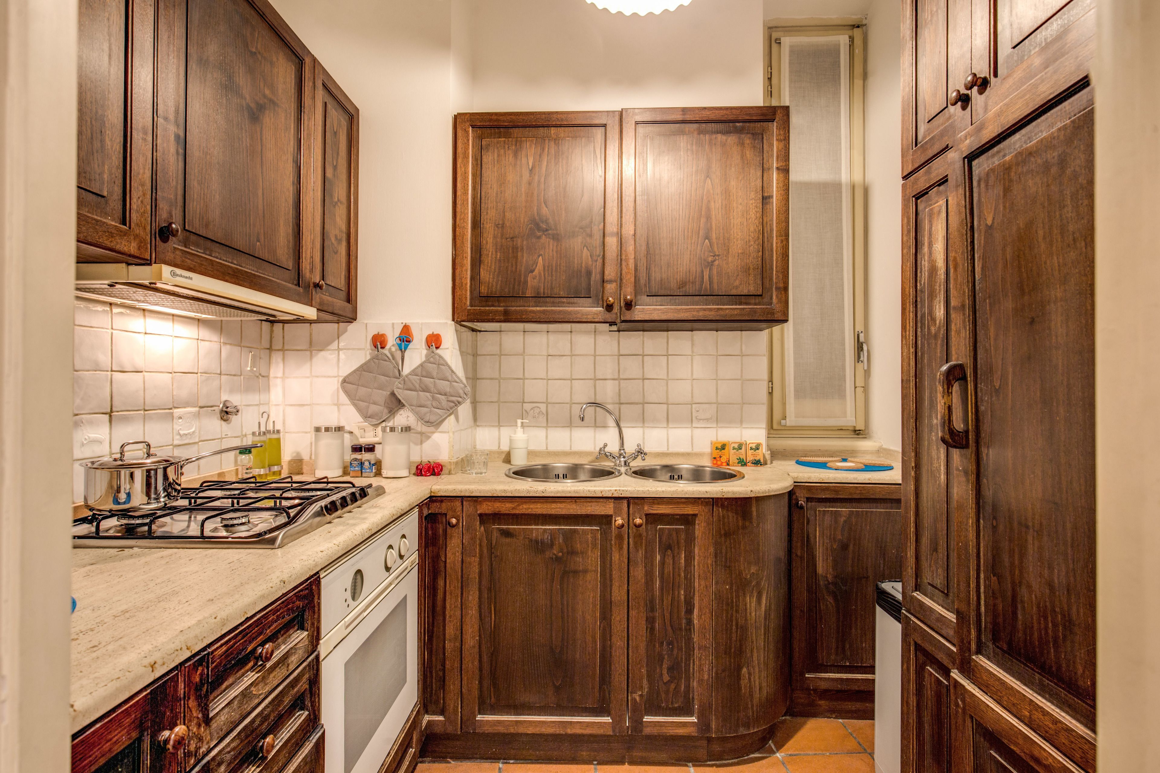 A kitchen with wooden cabinets, a stove, and a sink.