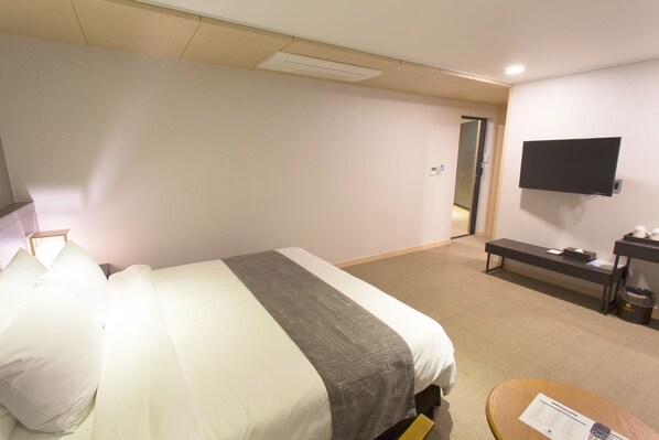 Une chambre d’hôtel équipée d’un lit, d’un bureau, d’une chaise, d’une télévision et d’une poubelle.