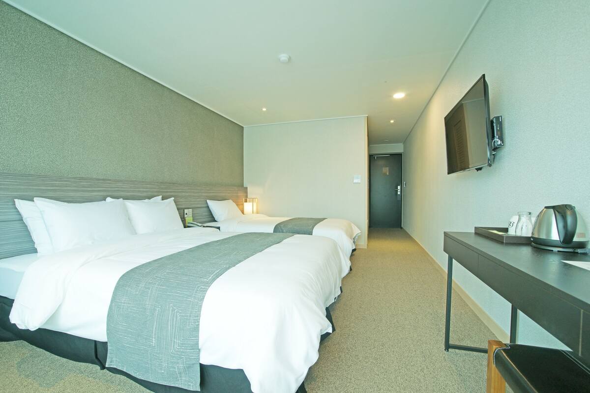 Habitación de hotel con una cama grande, mesitas de noche, un televisor de pantalla plana y una cafetera.