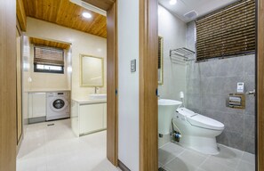 Un baño moderno con lavadora, lavamanos, inodoro y cabina de ducha de vidrio.