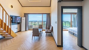 Moderni hotellihuone, jossa on puinen portaikko, ruokailutila ja parveke, jolta on näkymä.