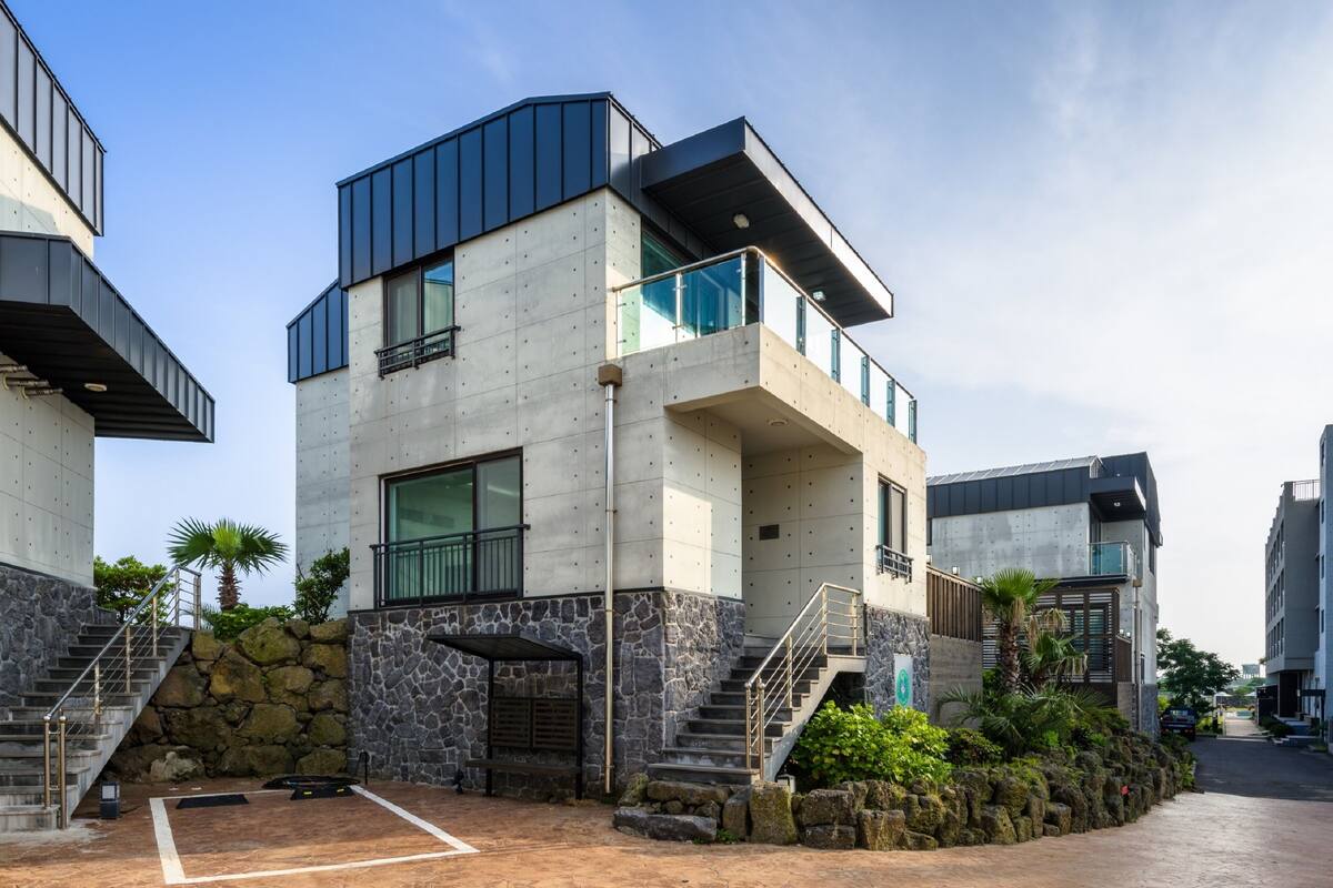A modern multi-story building with a concrete facade, large windows, and a stone accent wall.