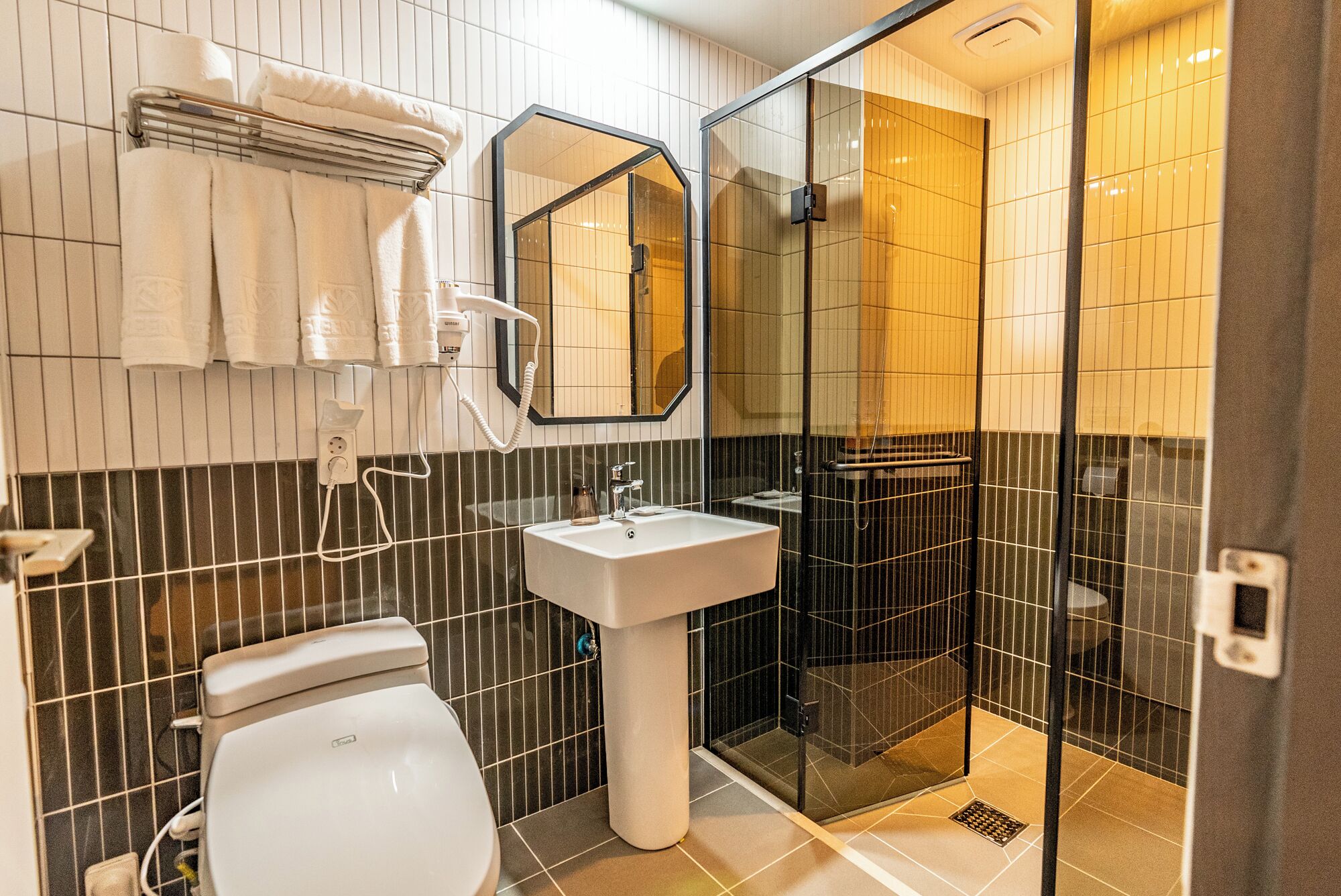 A modern bathroom with a toilet, sink, and glass-enclosed shower.
