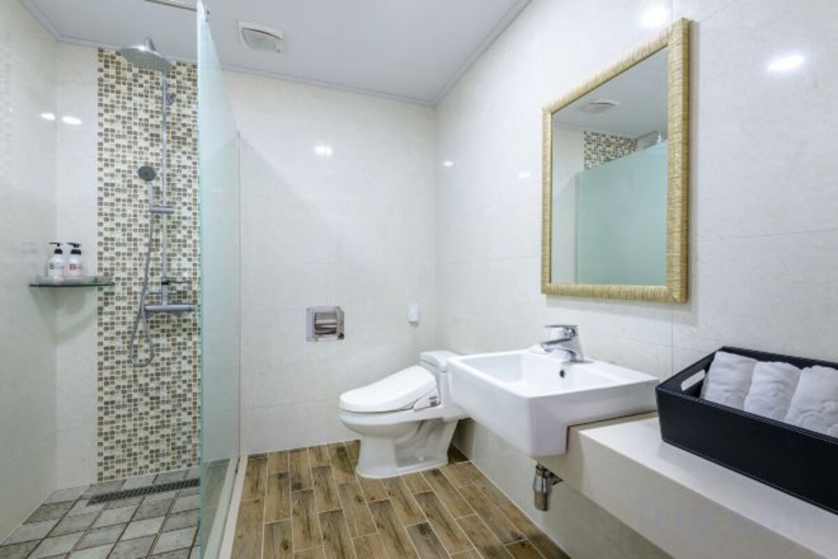 Une salle de bain équipée d’une douche, de toilettes, d’un lavabo et d’un miroir.
