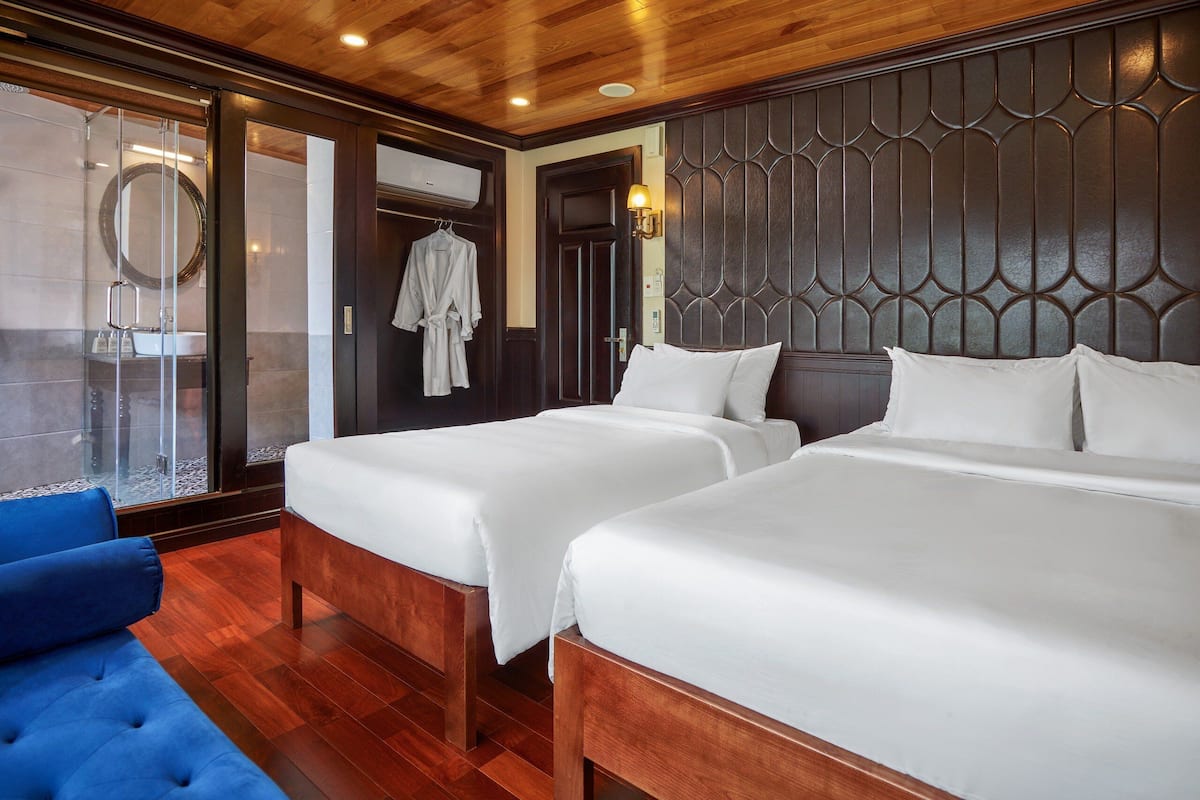 Une chambre d’hôtel avec deux lits, un canapé bleu, un grand miroir et un plafond en bois.
