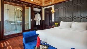 Ein Hotelzimmer mit einem großen Bett, einem blauen Sofa, einer begehbaren Glasdusche und einer Holzbalkendecke.