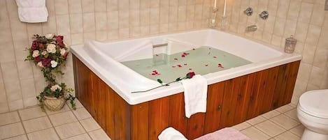 Un bagno con una vasca da bagno in legno, un water, un lavandino e un tappeto rosa.