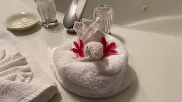A white towel with a red flower and a small pink item on a bathroom sink.