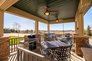 A covered patio with a grill, seating, and a view of the landscape.