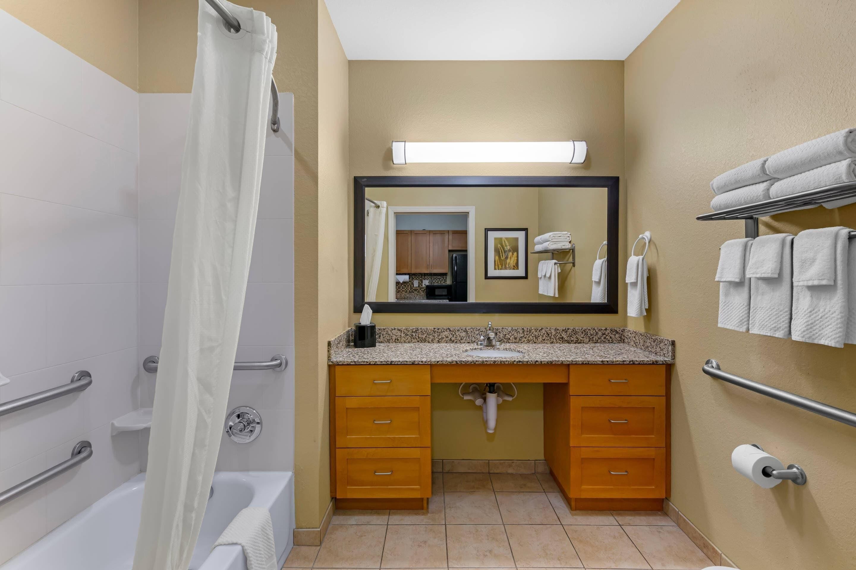 A bathroom with a shower, a sink with a mirror, and a towel rack.