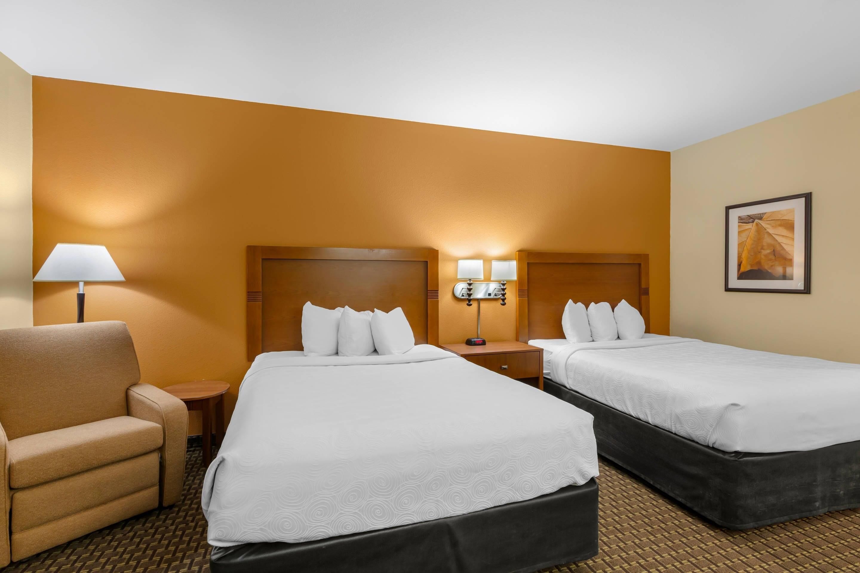 A hotel room with two beds, a sofa, a lamp, and a nightstand.