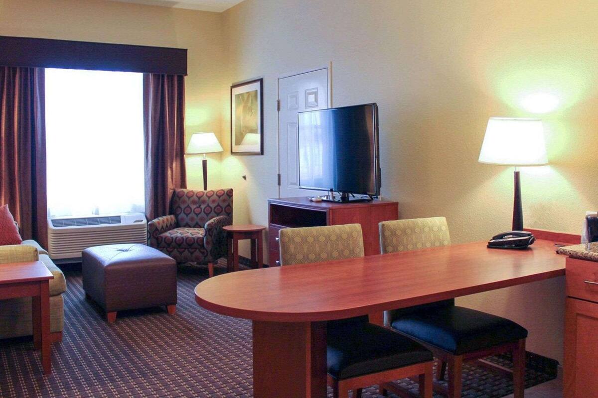 A hotel room with a dining area, a TV, and two lamps.