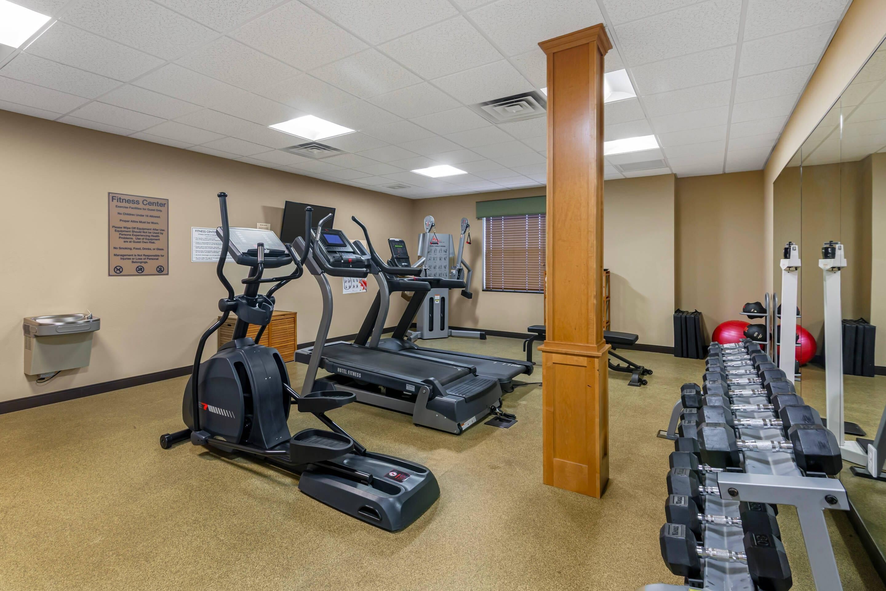 A fitness center with treadmills, elliptical machines, and a weight bench.