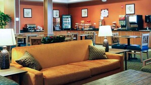 En hotellobby med en soffa, stolar, en kaffestation och en frukostbuffé.