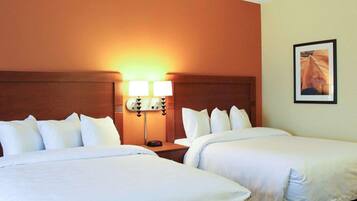 A hotel room with two beds, a nightstand with lamps, and a framed picture on the wall.