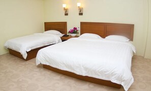 A hotel room with two single beds and a double bed, a nightstand with a vase of flowers, and wall-mounted lights. - Shwe Phyu Hotel (Mandalay)