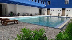Una piscina con sillas de descanso y plantas en macetas.