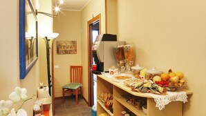 A narrow hallway with a dining area featuring a buffet table, a chair, and a red umbrella. - Residenza Il Fiore (Bergamo)