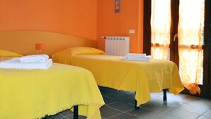 A hotel room with two beds, each covered with yellow sheets, and a window with orange curtains. - Residenza Il Fiore (Bergamo)