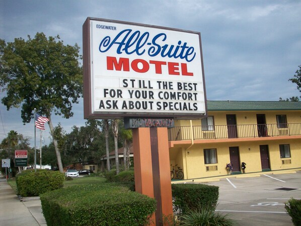 Un letrero de motel con el nombre 'All Suite Motel' y un mensaje sobre comodidad y ofertas especiales.