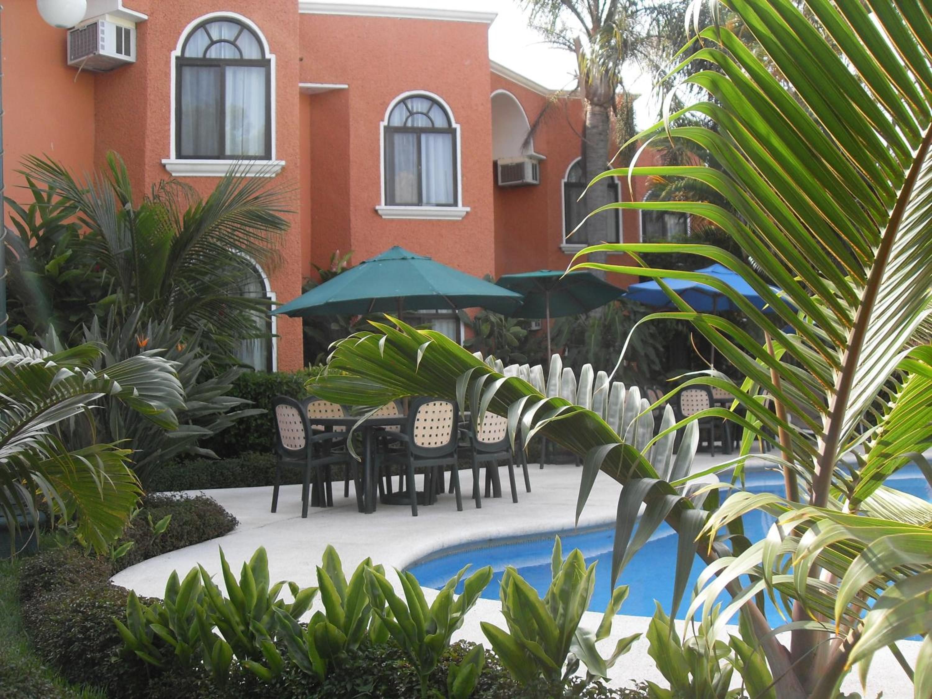 A pool area with outdoor seating and a building with arched windows.