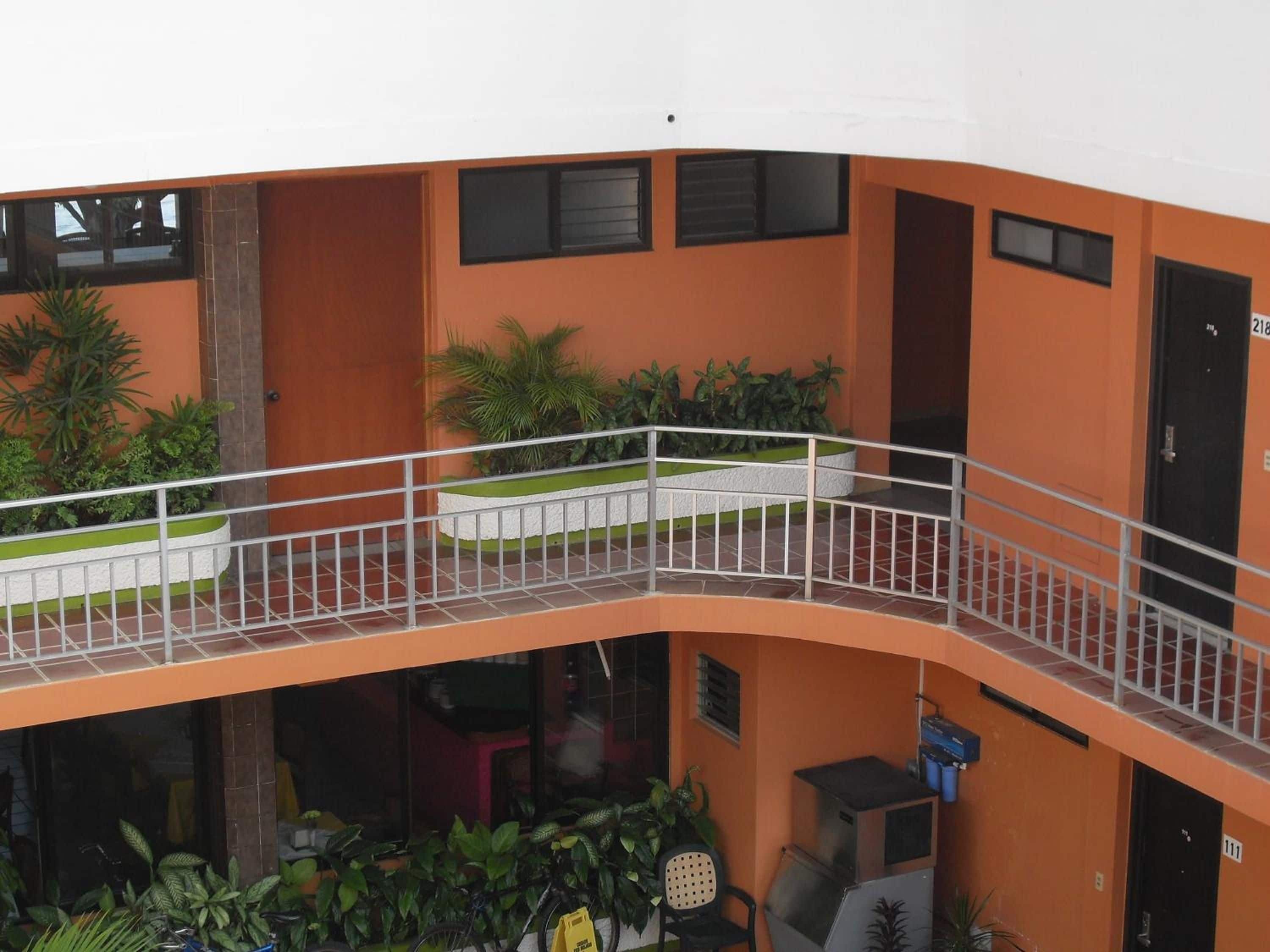 A multi-level building with balconies, outdoor seating, and potted plants.