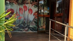 Escadaria que leva a um quarto com um mural tropical, uma porta de vidro e um corrimão de metal.