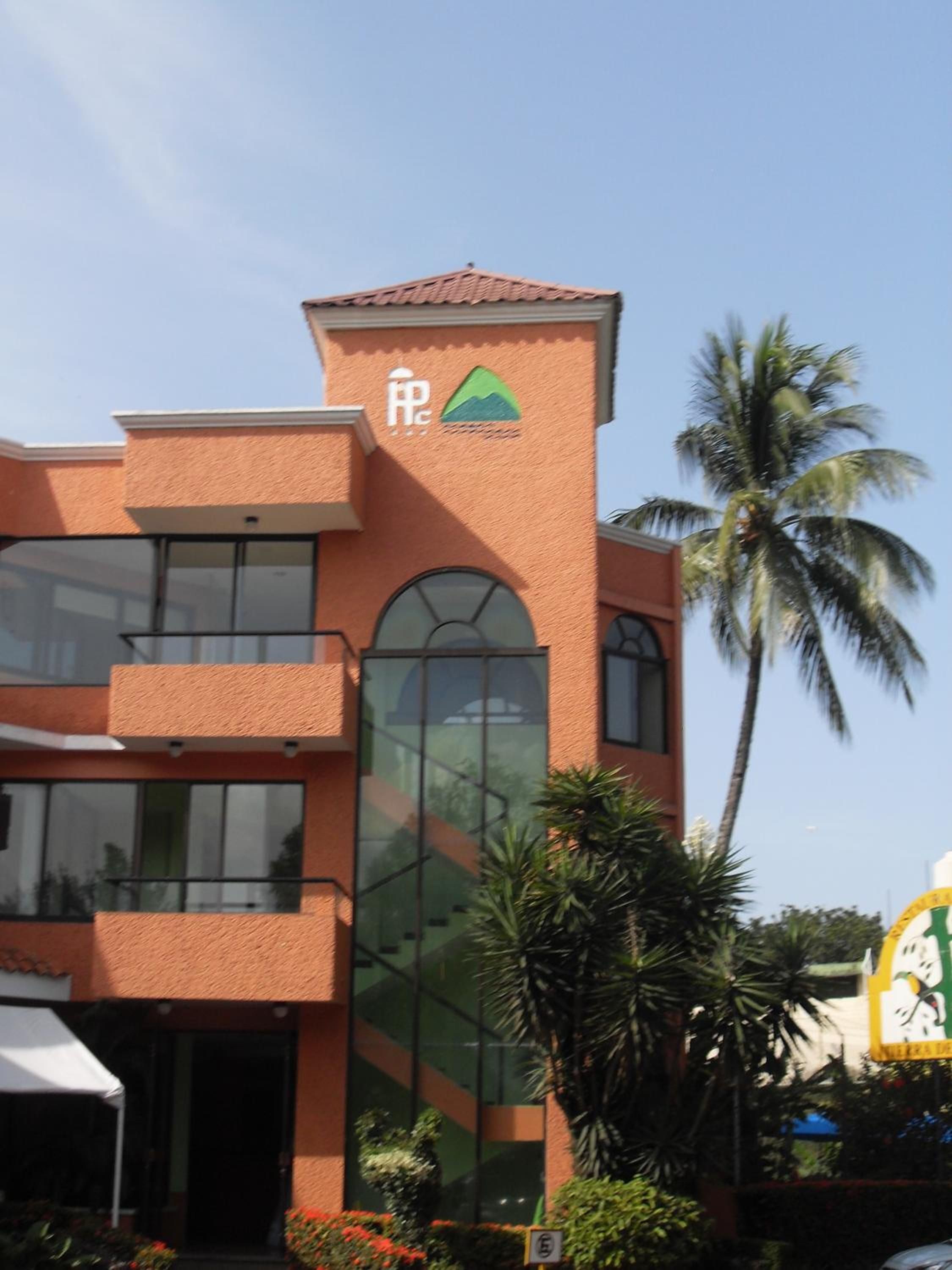 A building with a distinctive architectural style, featuring a prominent tower with a logo, large windows, and a balcony.