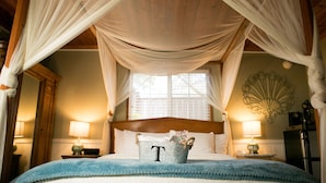 Un dormitorio con cama a dosel, un cubo con la letra 'T' sobre la cama y una concha decorativa en la pared.