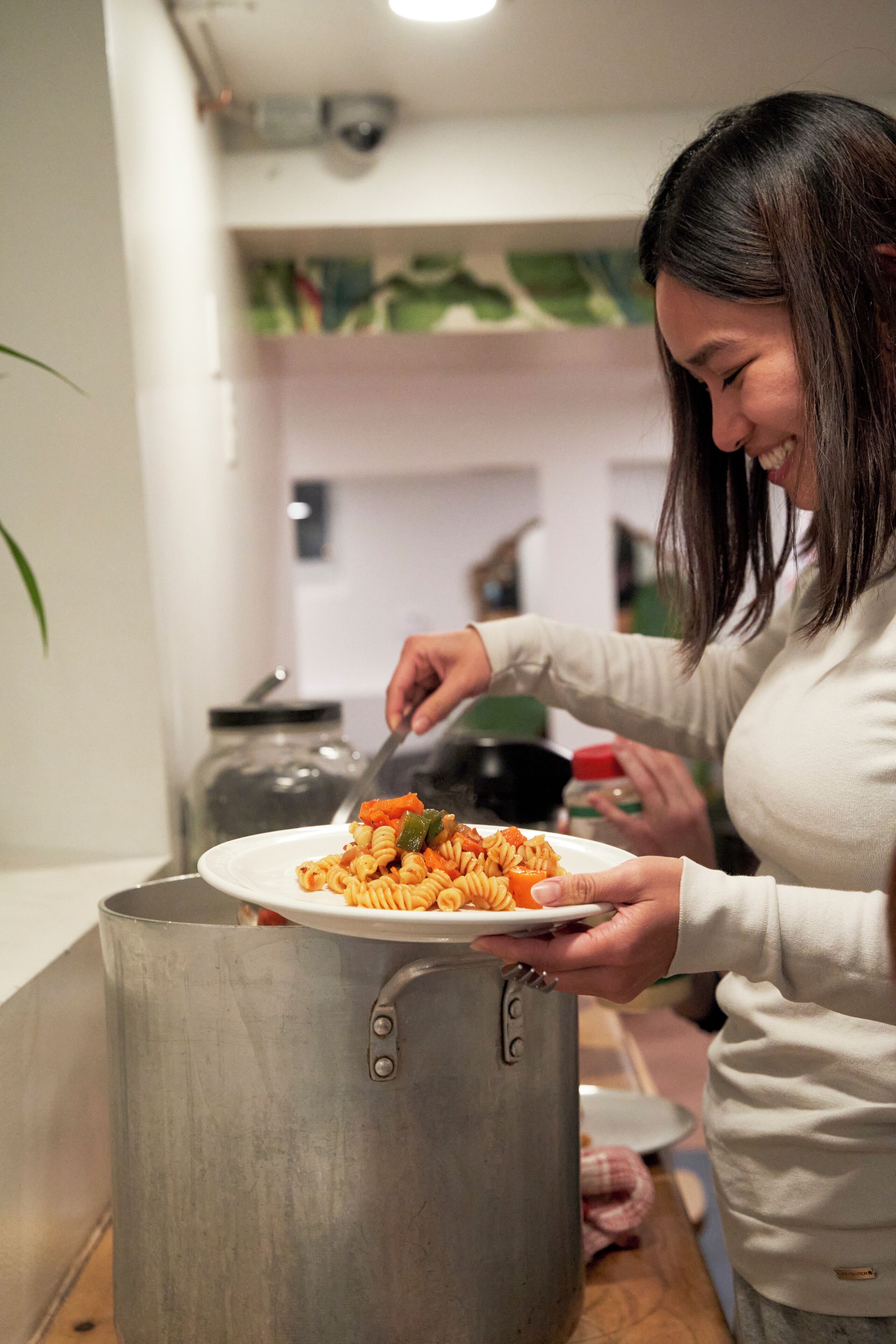 A person serving pasta from a large pot.