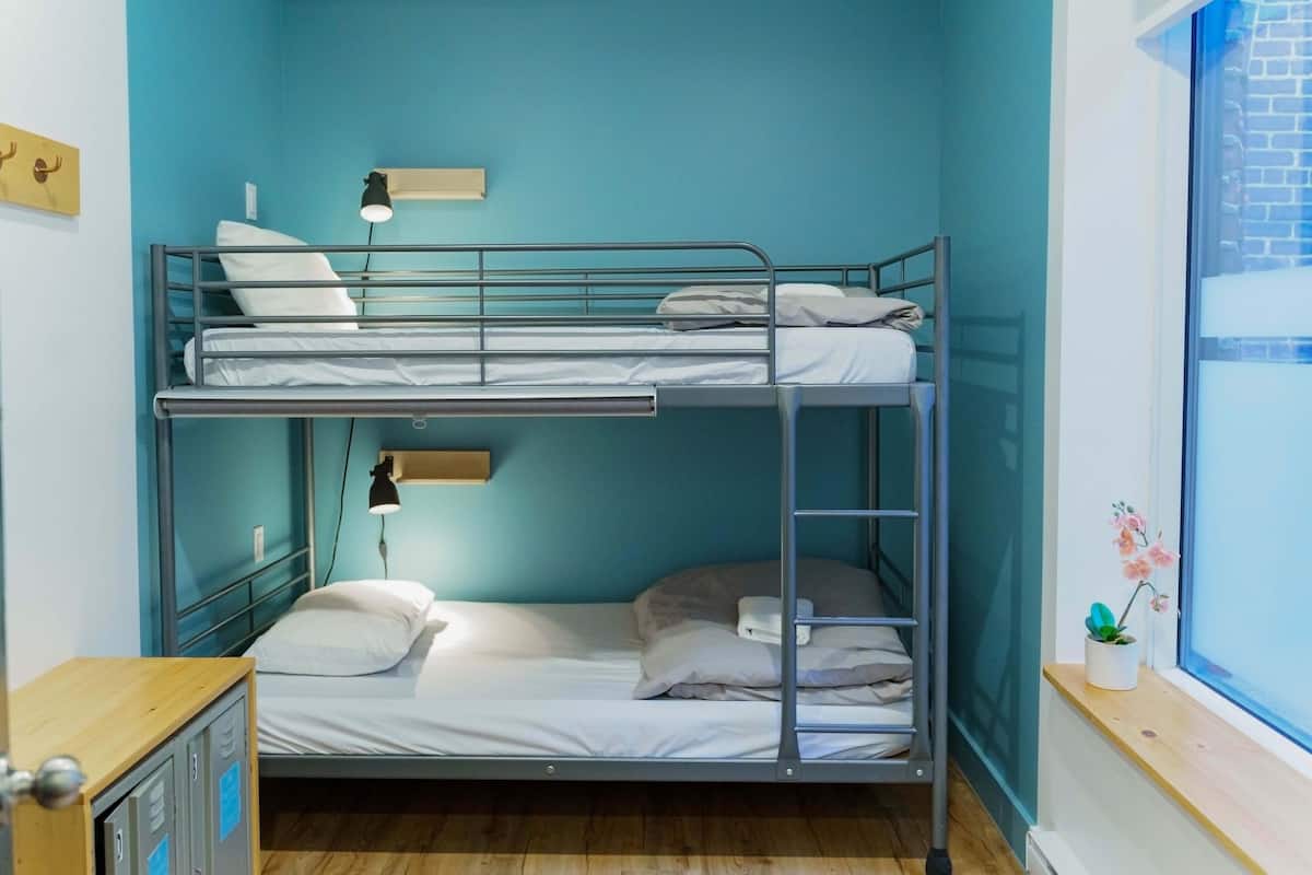 A bunk bed room with a desk, a lamp, and a window with a view.