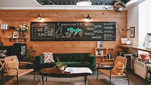 L’intérieur d’un café chaleureux, avec un mur en bois, un tableau noir servant de menu et un canapé vert.