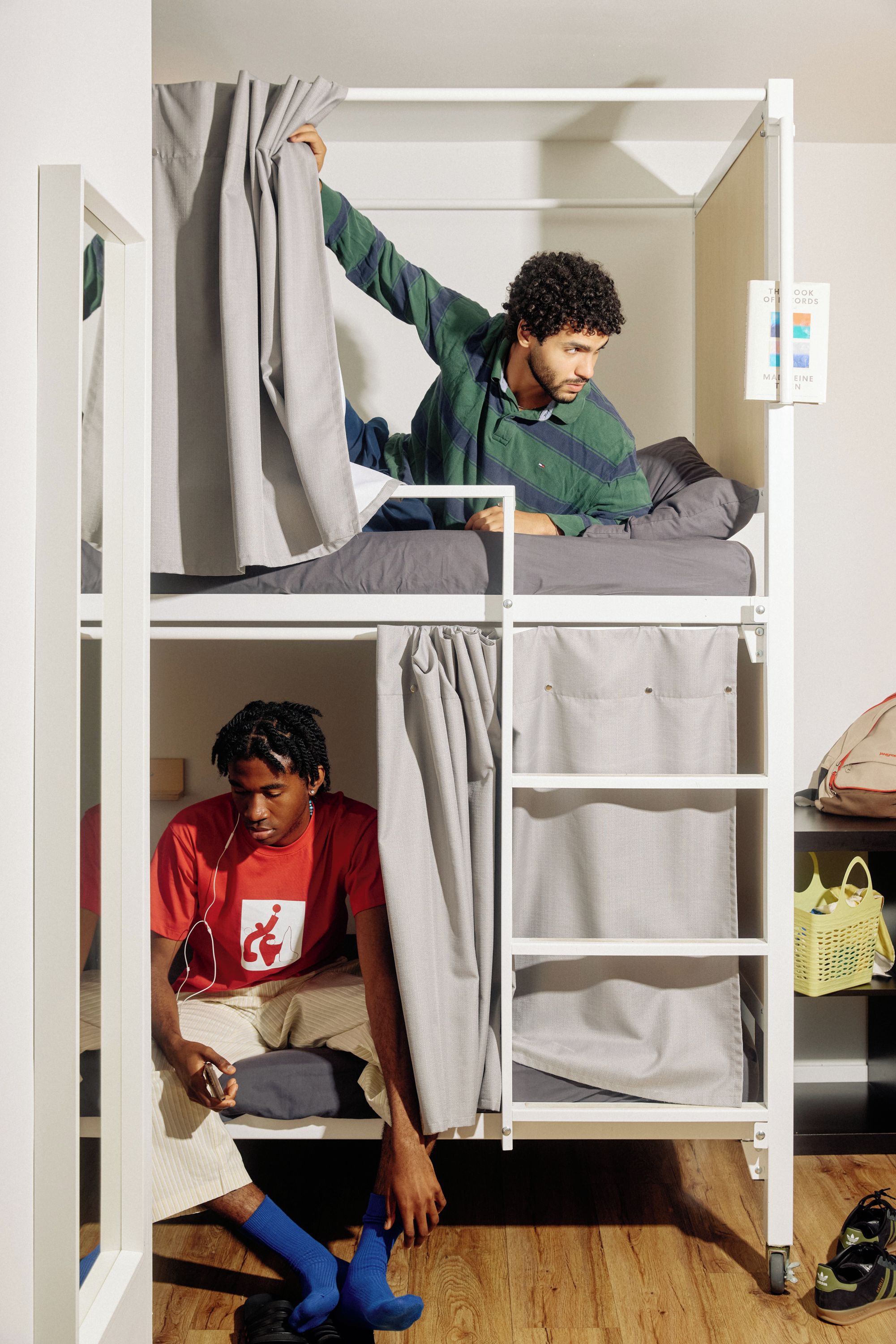 A bunk bed with a person standing on the top bunk and another sitting on the bottom.