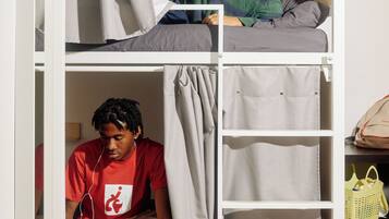 A bunk bed with a person standing on the top bunk and another sitting on the bottom.