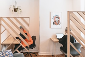 A modern office space with two workstations, a hanging plant, and a framed artwork on the wall. - Auberge Saintlo Montréal  - Hostel (Montreal)