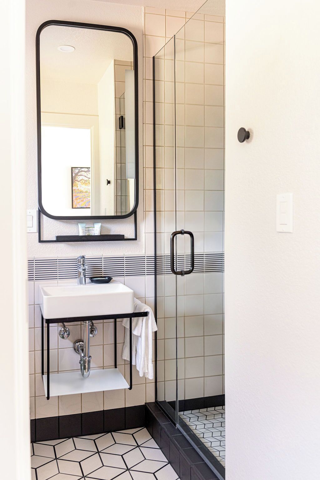 Une salle de bain avec un lavabo blanc, un miroir et un espace douche.