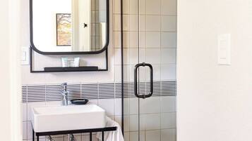 Une salle de bain avec un lavabo blanc, un miroir et un espace douche.
