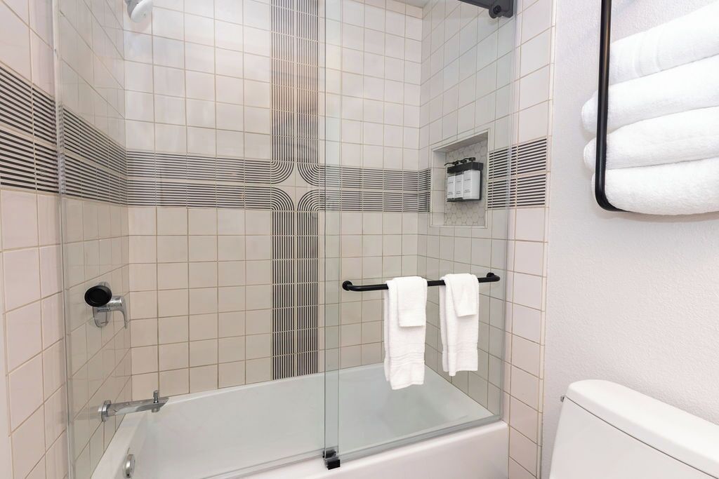 A modern bathroom with a glass-enclosed shower, a bathtub, and a toilet.