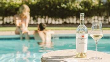 A bottle of Rutherford Wines Sauvignon Blanc and a glass on a stone table by a pool.