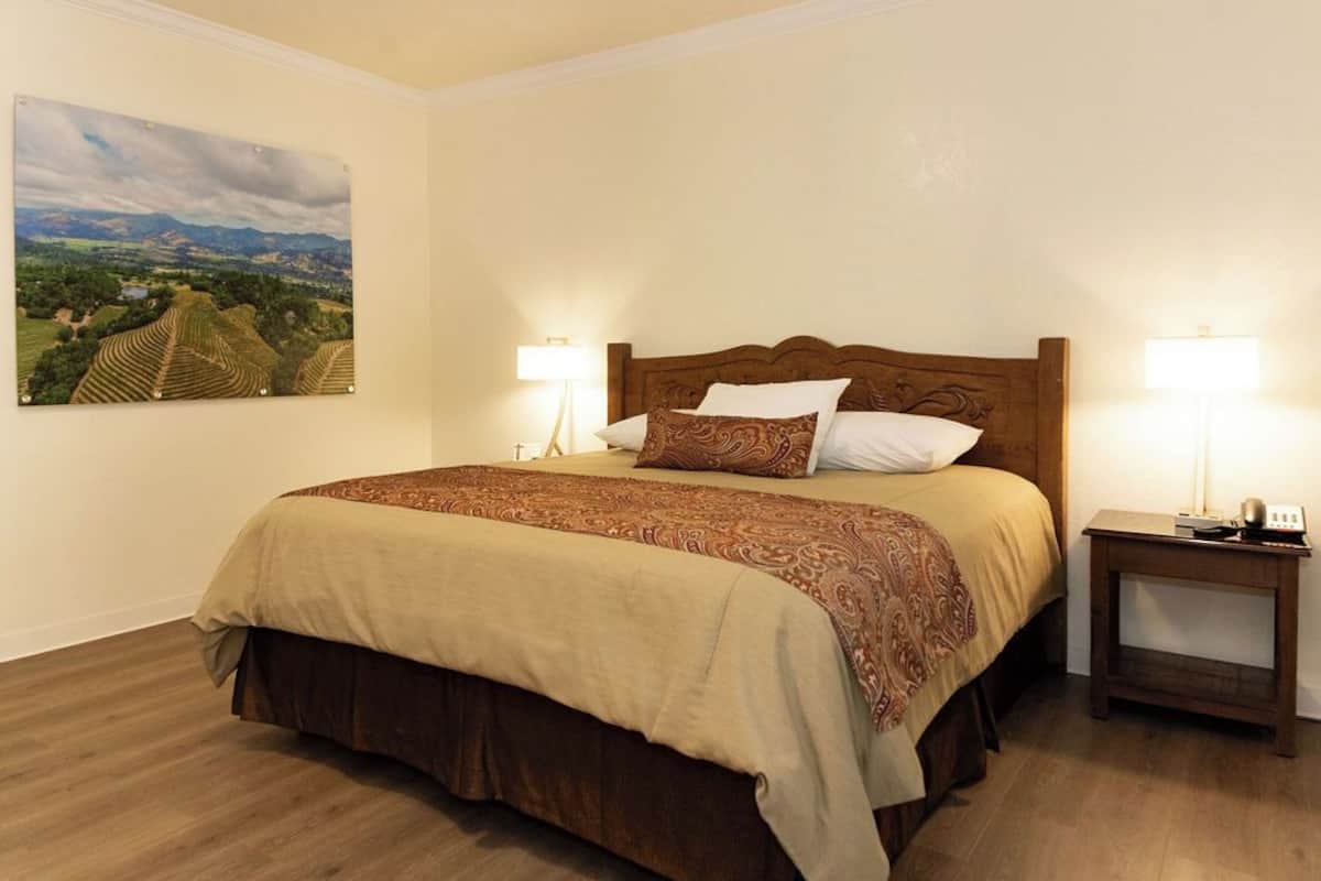 A neatly made bed with a patterned bedspread, two bedside lamps, and a nightstand with a lamp.