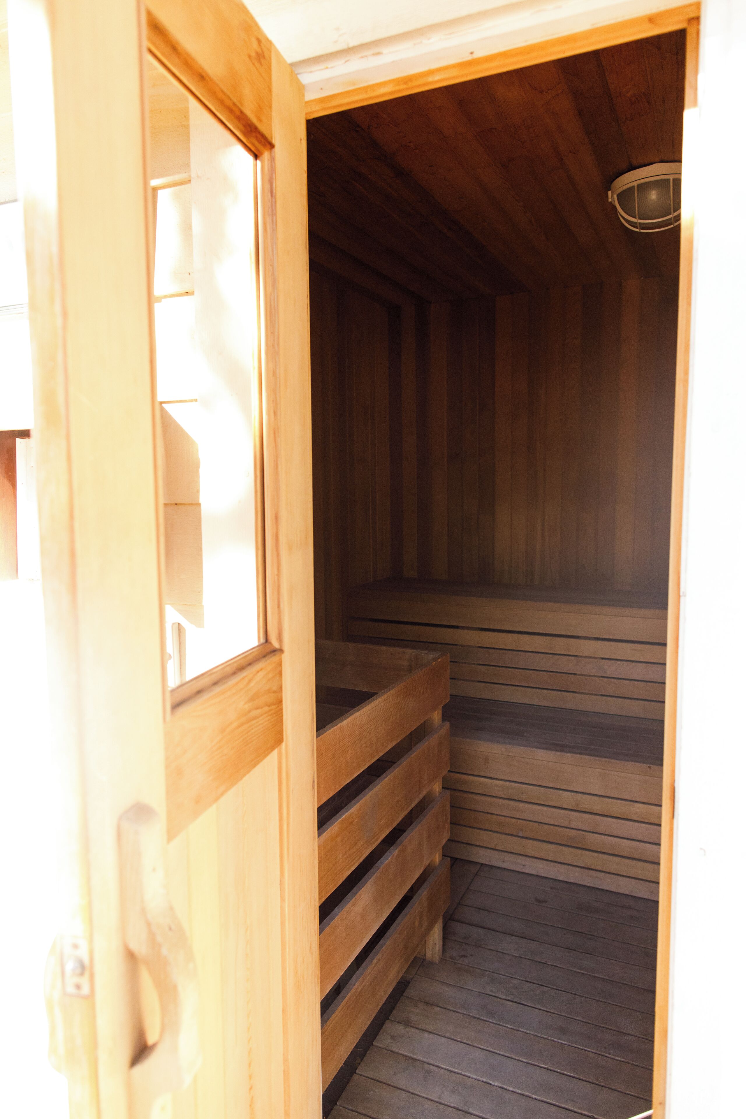A wooden sauna with a sloped floor and a wooden door.
