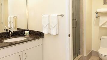 A bathroom with a sink, mirror, towel rack, shower, and toilet.