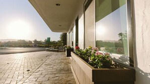 A building with large windows, a stone-paved walkway, and flower planters.