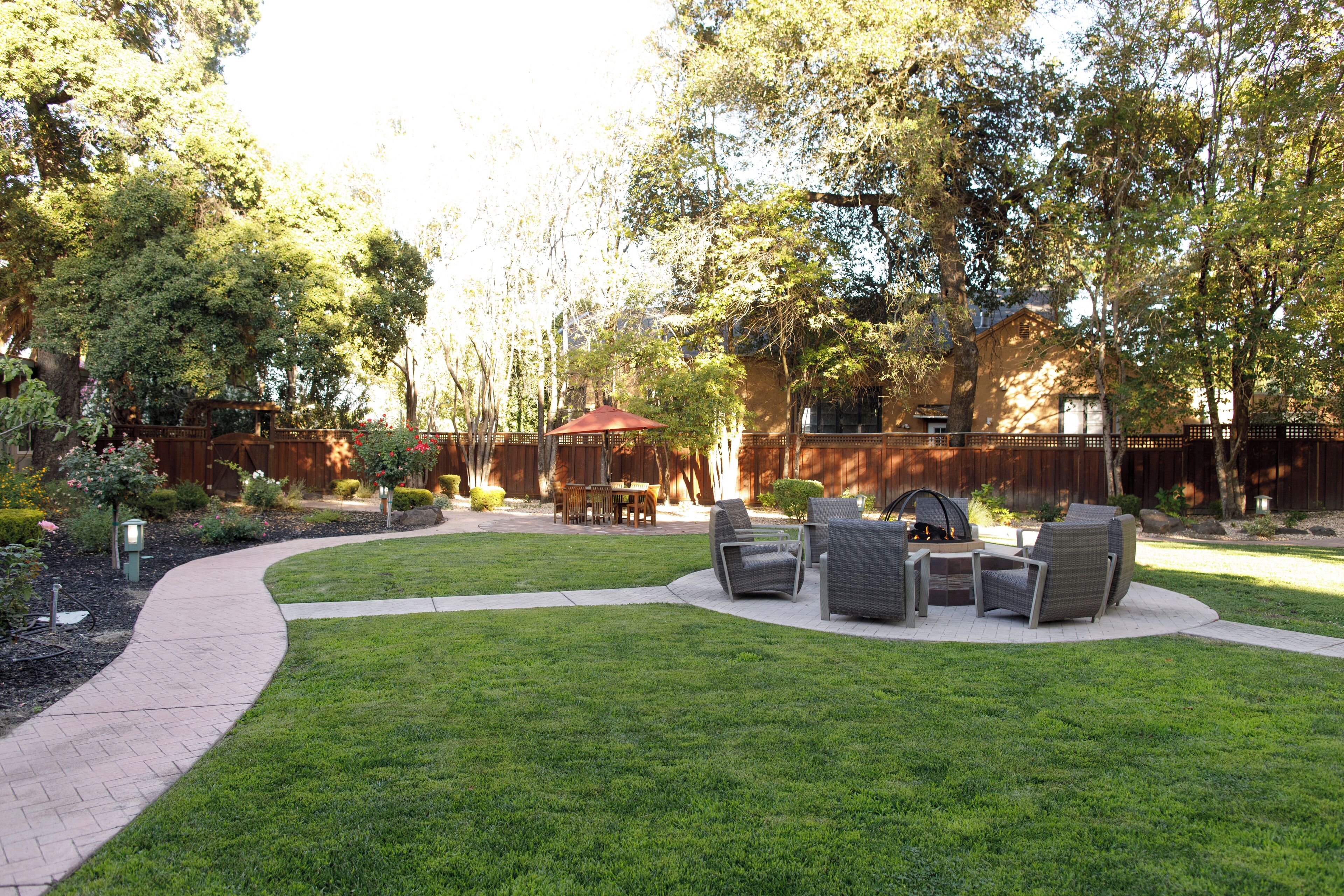 A backyard with a paved patio, outdoor furniture, and a wooden fence.