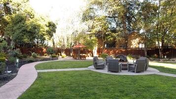 A backyard with a paved patio, outdoor furniture, and a wooden fence.