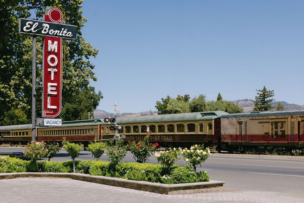 A vintage El Bonita Motel sign with a train in the background.