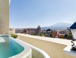 Una piscina en la azotea con vistas despejadas a un edificio histórico y montañas al fondo.