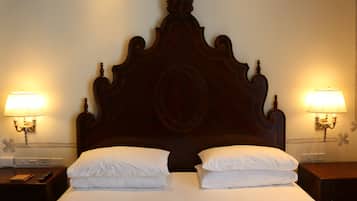 Una cama bien hecha con cabecera de madera, dos lámparas de noche y una mesita de noche con un control remoto.