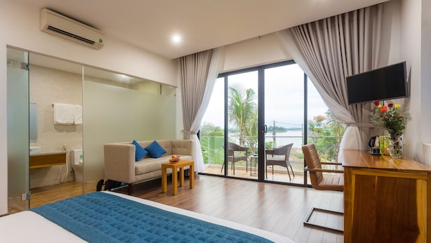 Hotelkamer met een bed, een bank, een televisie, een balkon met uitzicht en een bureau.